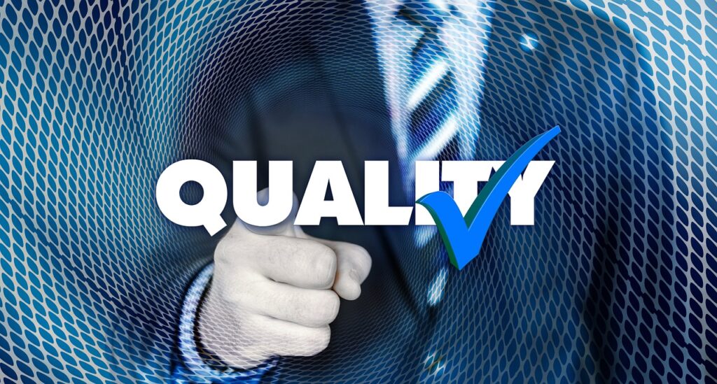 Businessman pointing at the word Quality with a check mark by it.