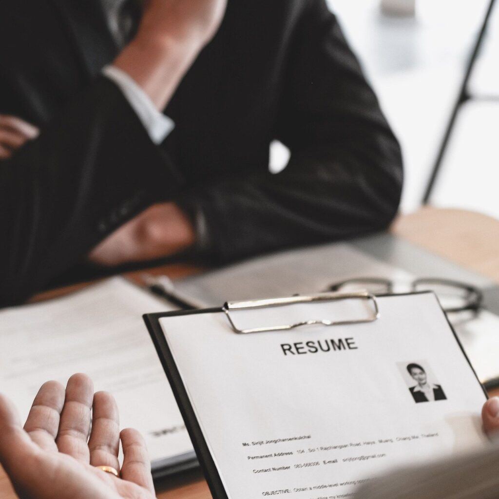 Resume on a clipboard, with two people talking.