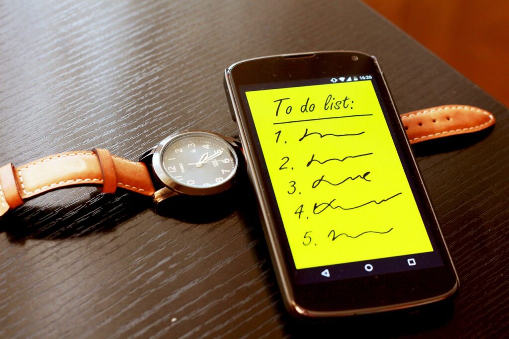 Wrist watch next to phone with a To Do list displayed.