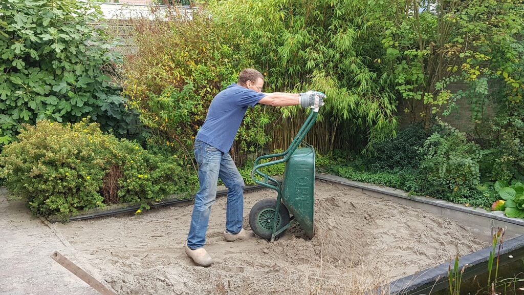 Man dumping a wheelbarrow full of gravel.