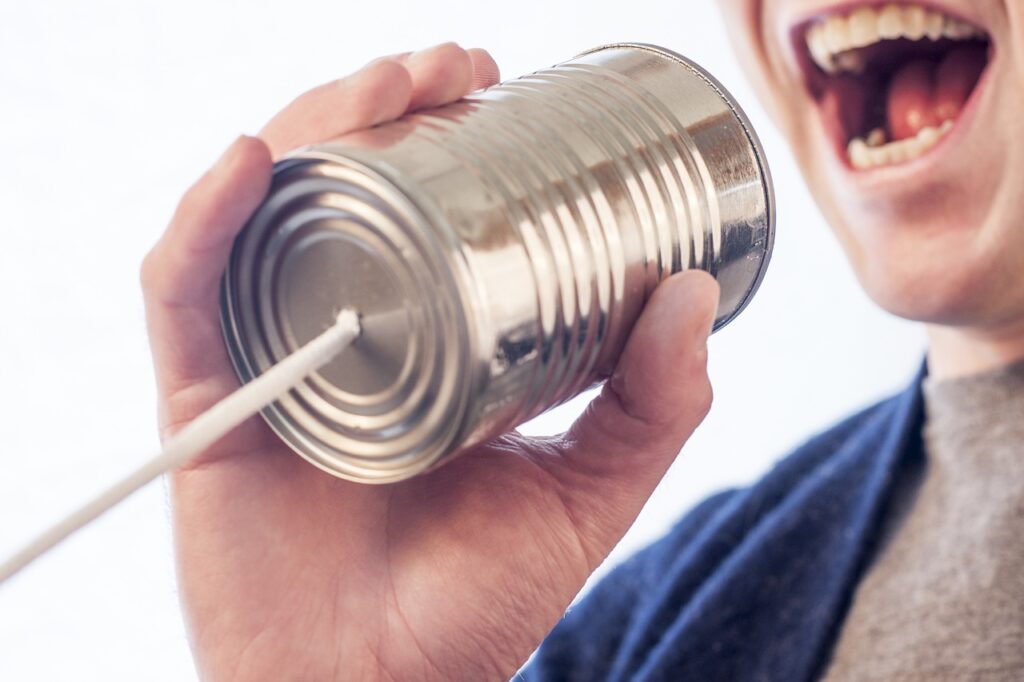 A person talking into a can with a string connection.