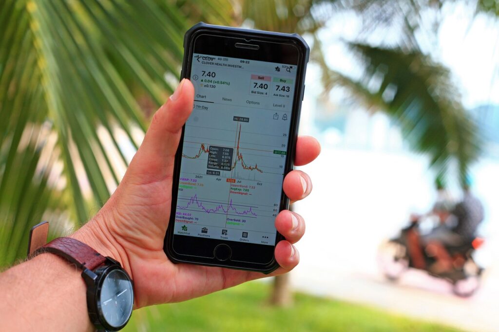 A hand holding a cell phone with a palm tree in the background.