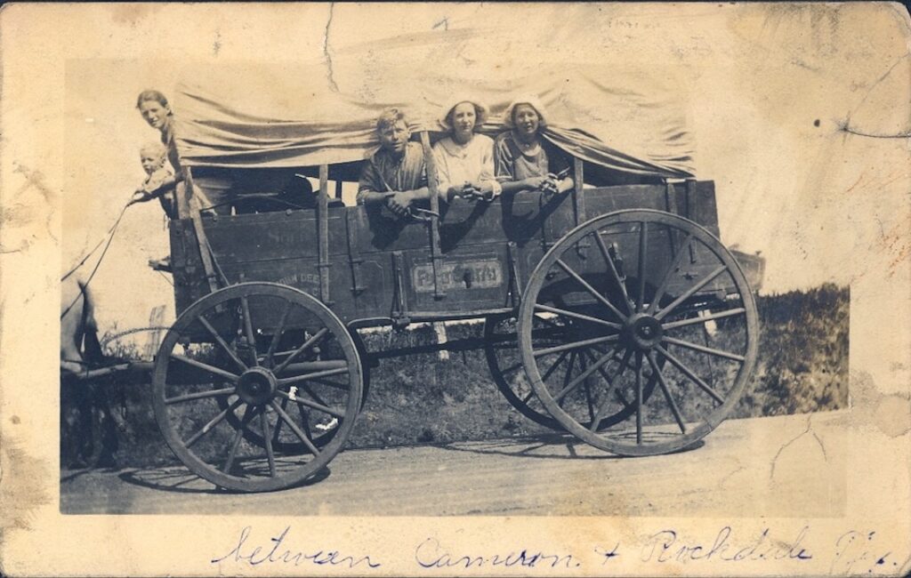 A photo of kids in a covered wagon on the frontier.