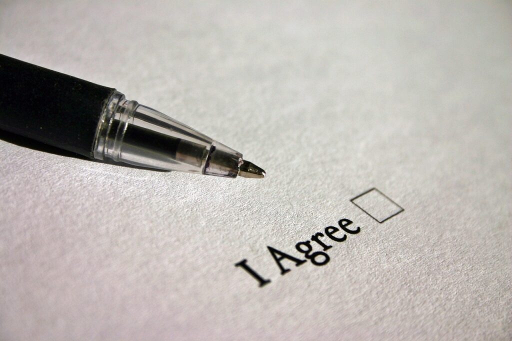 A document with a pen laying on it next to "I Agree" and a box to check.