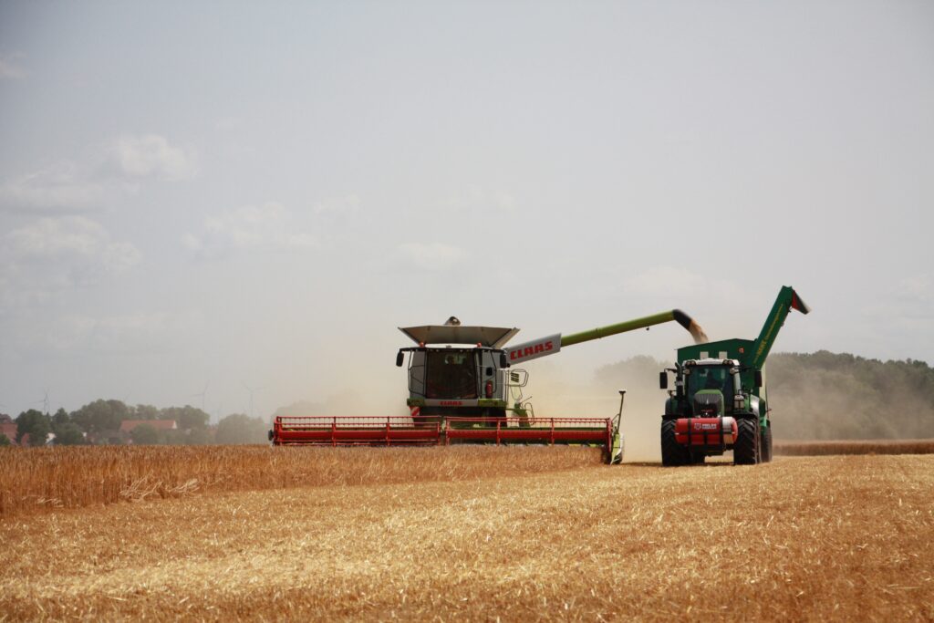 Combine harvesting grain and unloading into a grain hauler truck.
