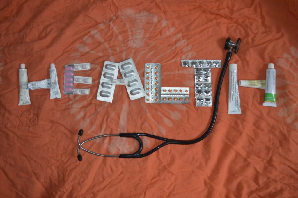 The word Health spelled out with pill packs and a stethoscope laid over it.