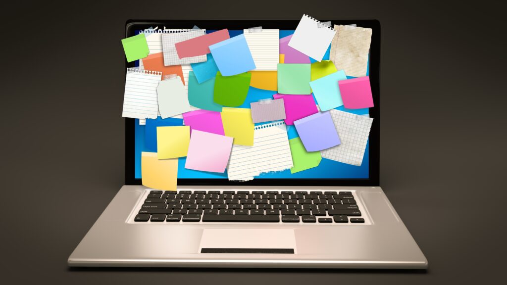 A laptop computer with sticky notes all over the screen.