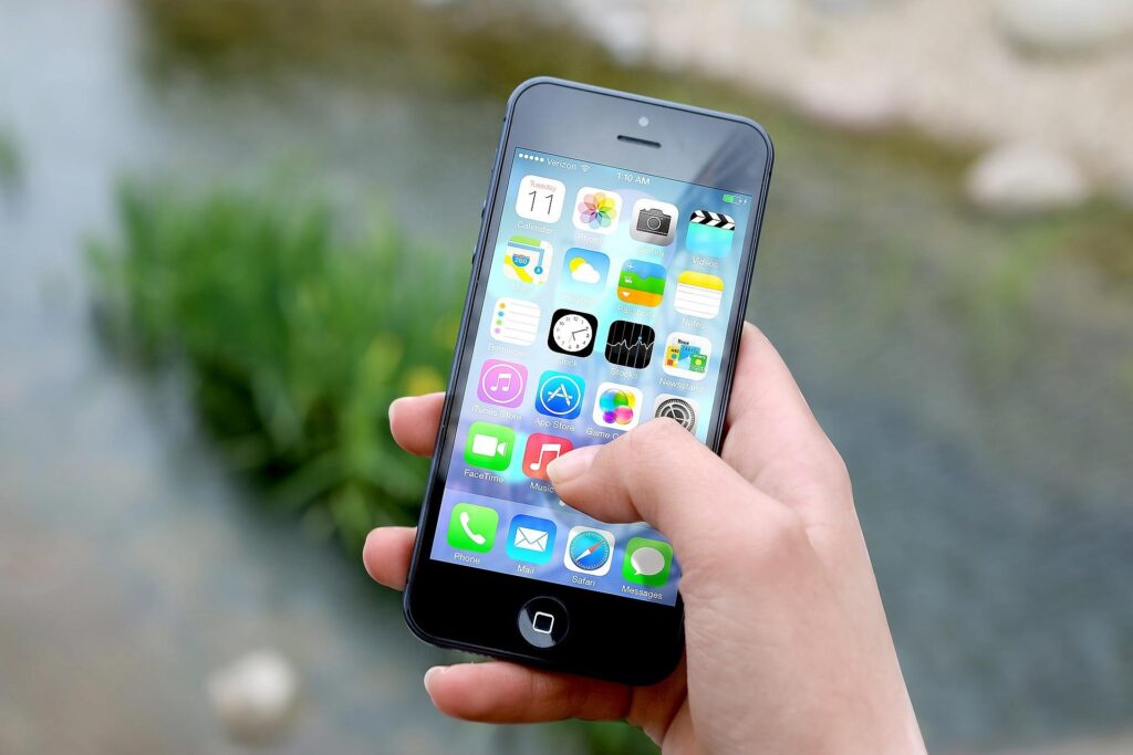 A woman holding an iPhone with a lot of apps.