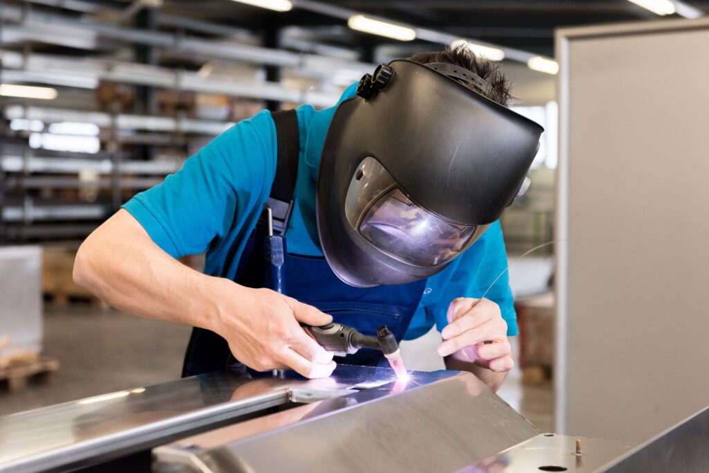 A person welding on metal with a welder's hood on.