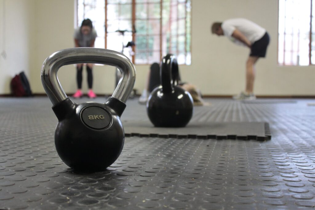 A couple in a gym bent over after working out with kettlebells.